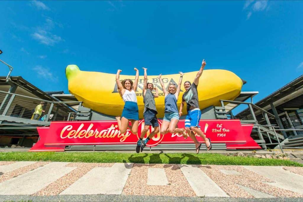 A group of four people jumping in front of the big banana